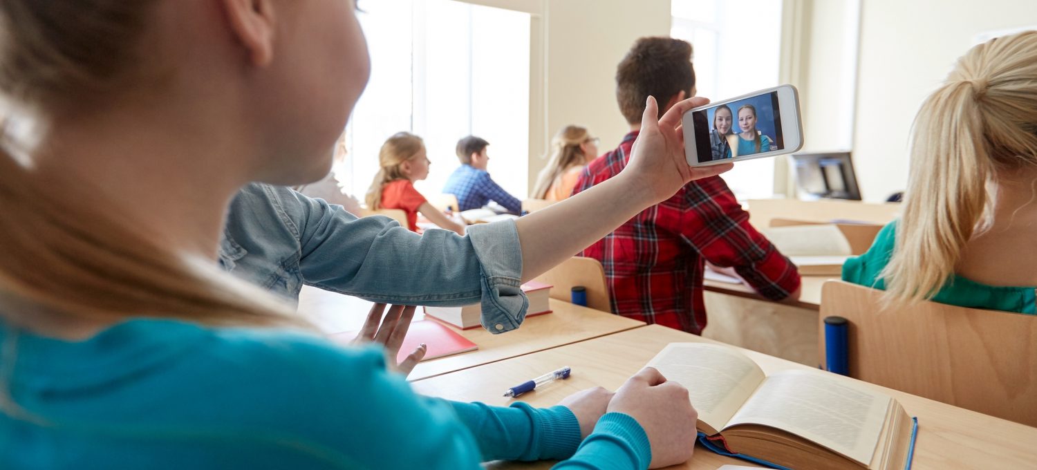 Schüler fotografieren mit Handy im Unterricht