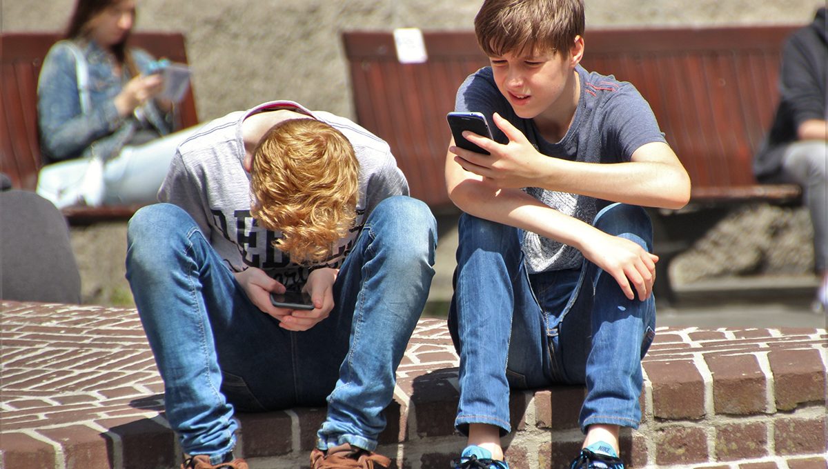 Zwei Kinder sitzen auf dem Boden und nutzen ihre Smartphones