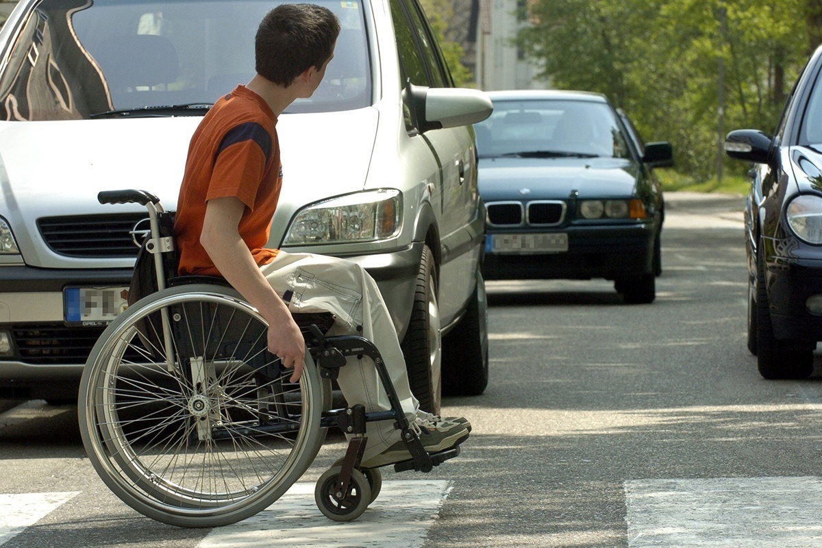 Ein Rollstuhlfahrer fährt über einen Zebrastreifen