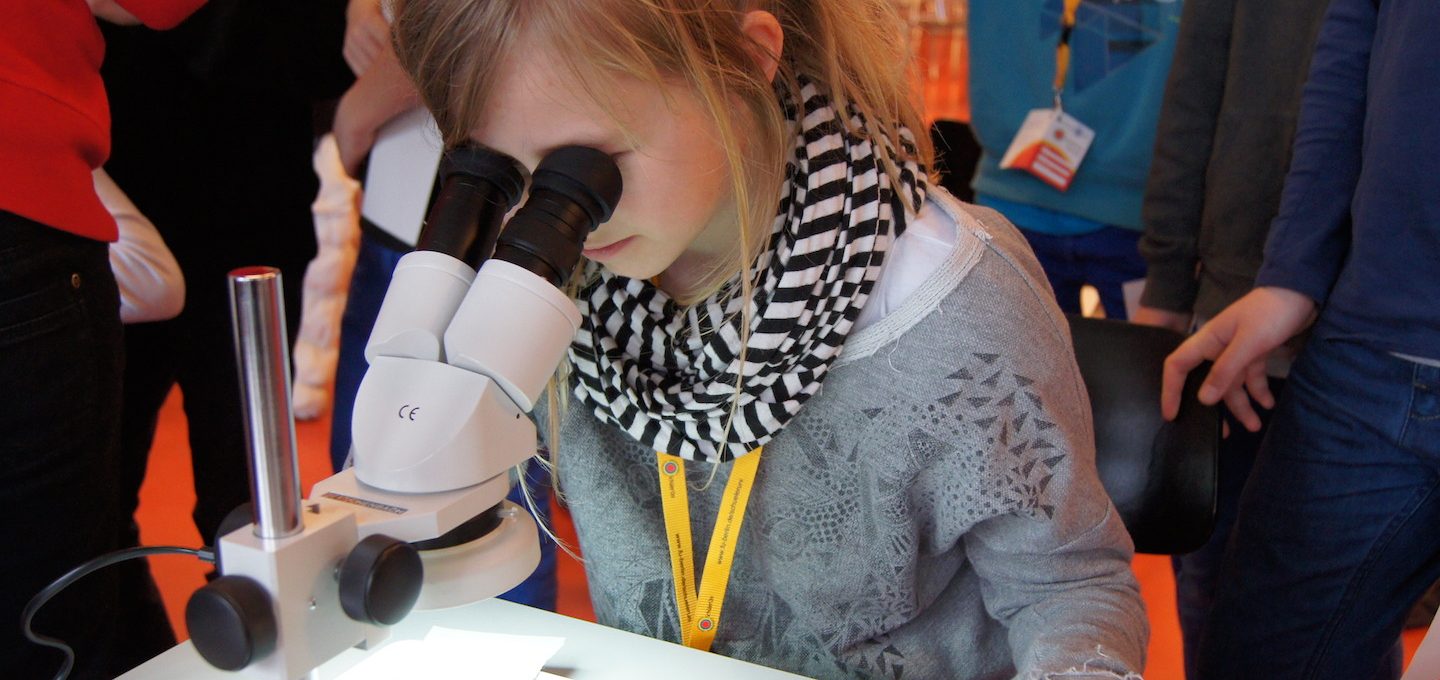 Mädchen schaut durch Mikroskop